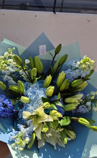 Ramo de flores azules y blancas envuelto en papel celeste